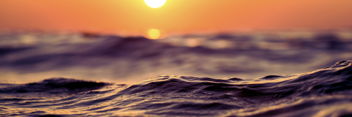 ocean water with setting sun in background