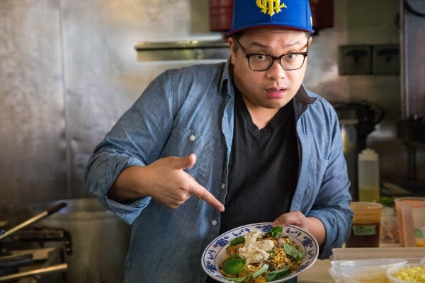 chef dale talde in his brooklyn restaurant, pointing proudly at a finished noodle dish