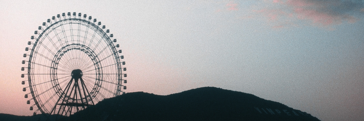 photograph of ferris wheel silhouette against a blue and pink sky