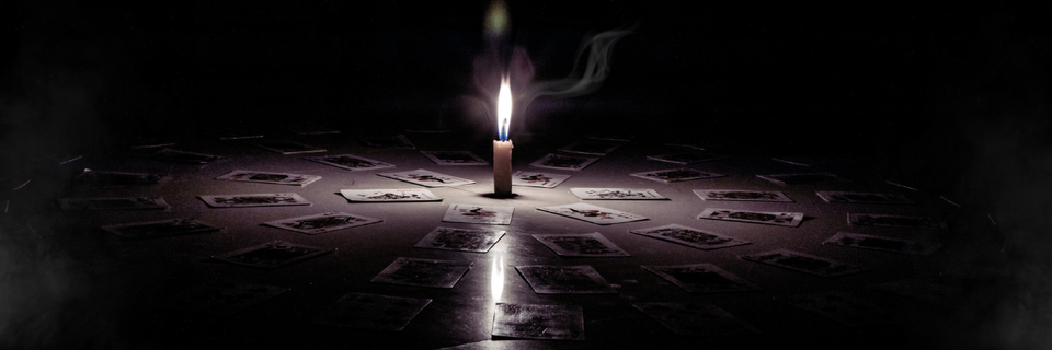 cards laid on the floor, arranged around a single burning candle in the center